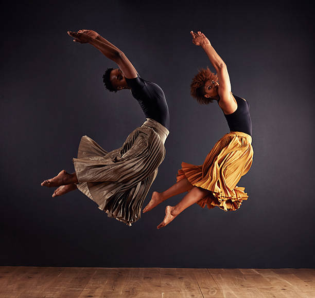Two contemporary dancers performing a synchronized leap in front of a dark backgroundhttp://195.154.178.81/DATA/shoots/ic_784287.jpg